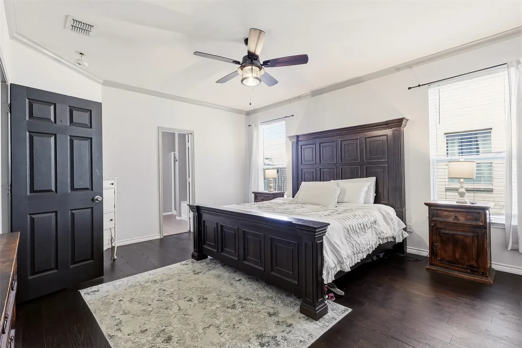 Spacious bedroom with a wooden bed, nightstand, and ceiling fan.